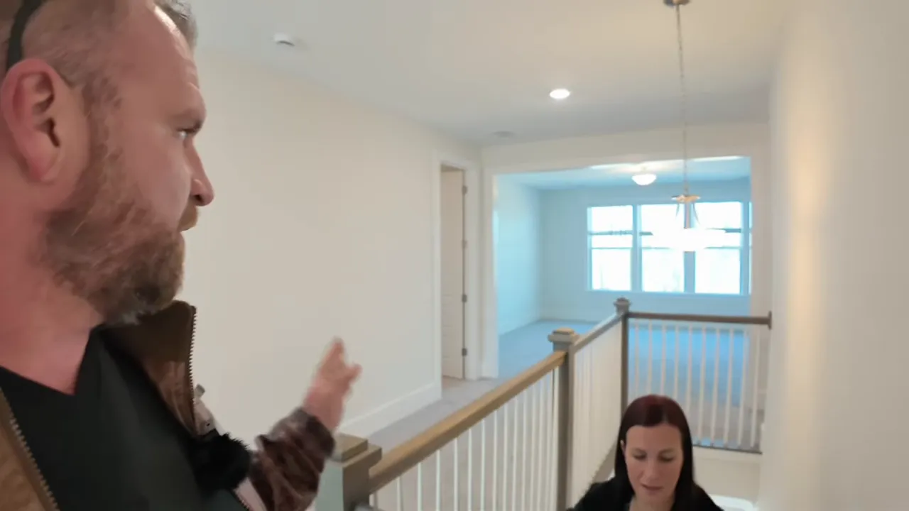 Upstairs landing with railing and a large open flex room visible; host gesturing toward the space