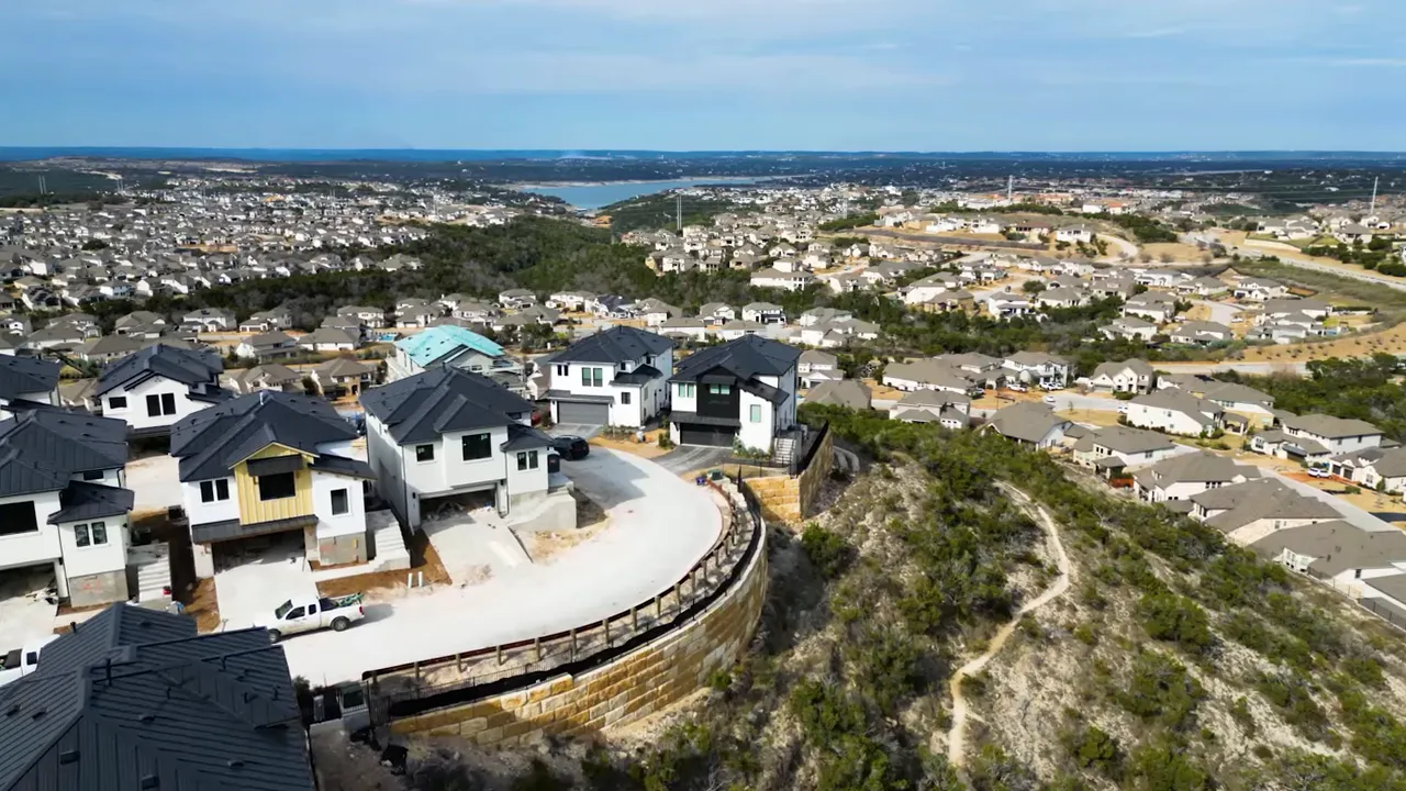 Aerial drone shot of hillside residential development with a lake on the horizon