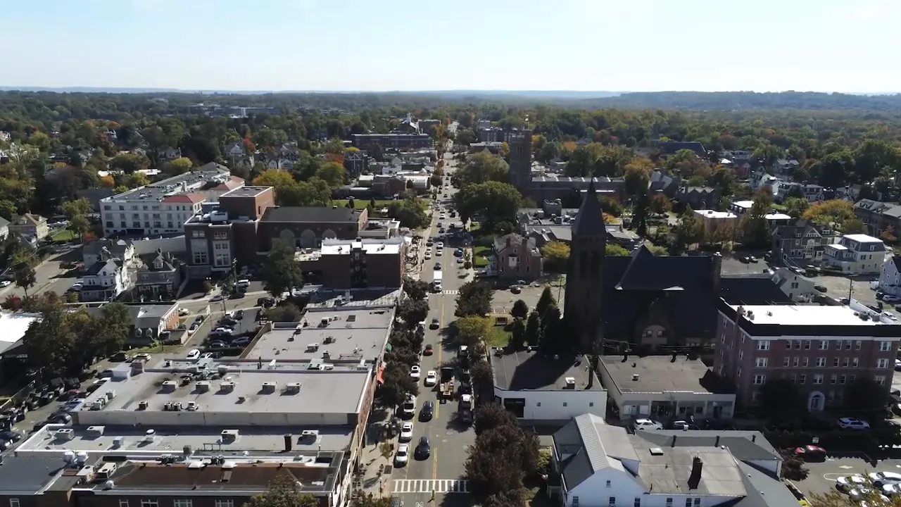 Aerial view of a larger downtown area with multiple buildings streets and church steeple