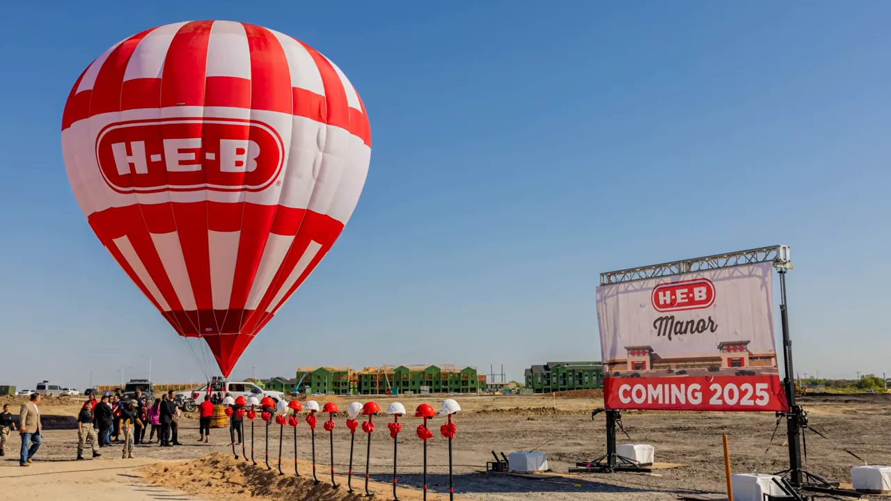 H‑E‑B balloon and a 'Coming 2025' sign at the Manor development site, showing the upcoming grocery anchor.