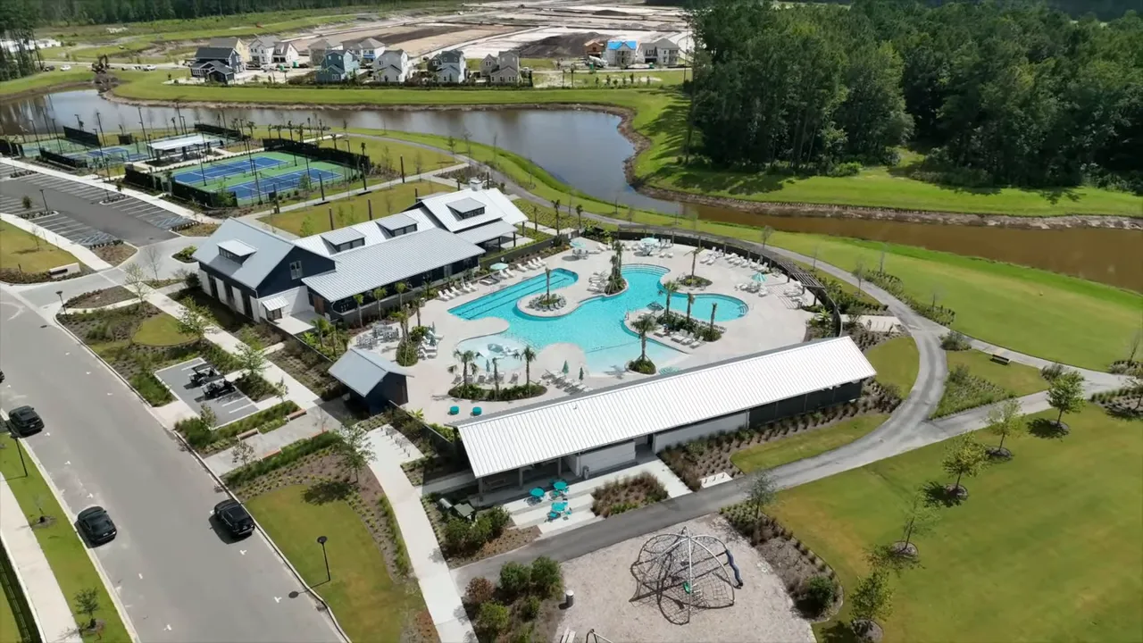 Aerial view of a neighborhood clubhouse, resort-style pool, playground and nearby homes.