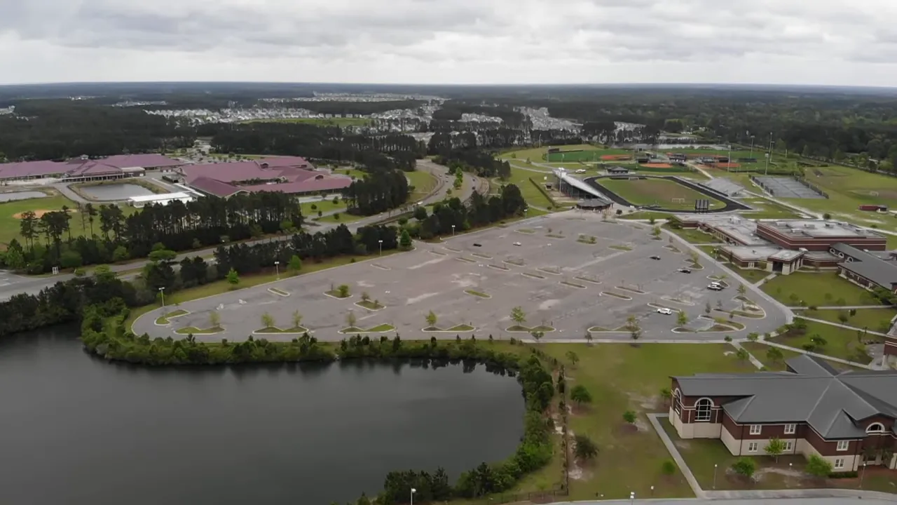 Aerial drone view of a school campus, parking lot, athletic fields and nearby ponds