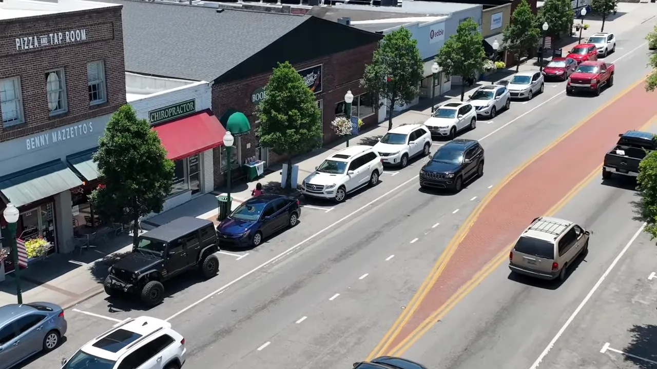 Aerial view of a downtown Summerville street with parked cars, moving vehicles, and a brick median showing typical local traffic.