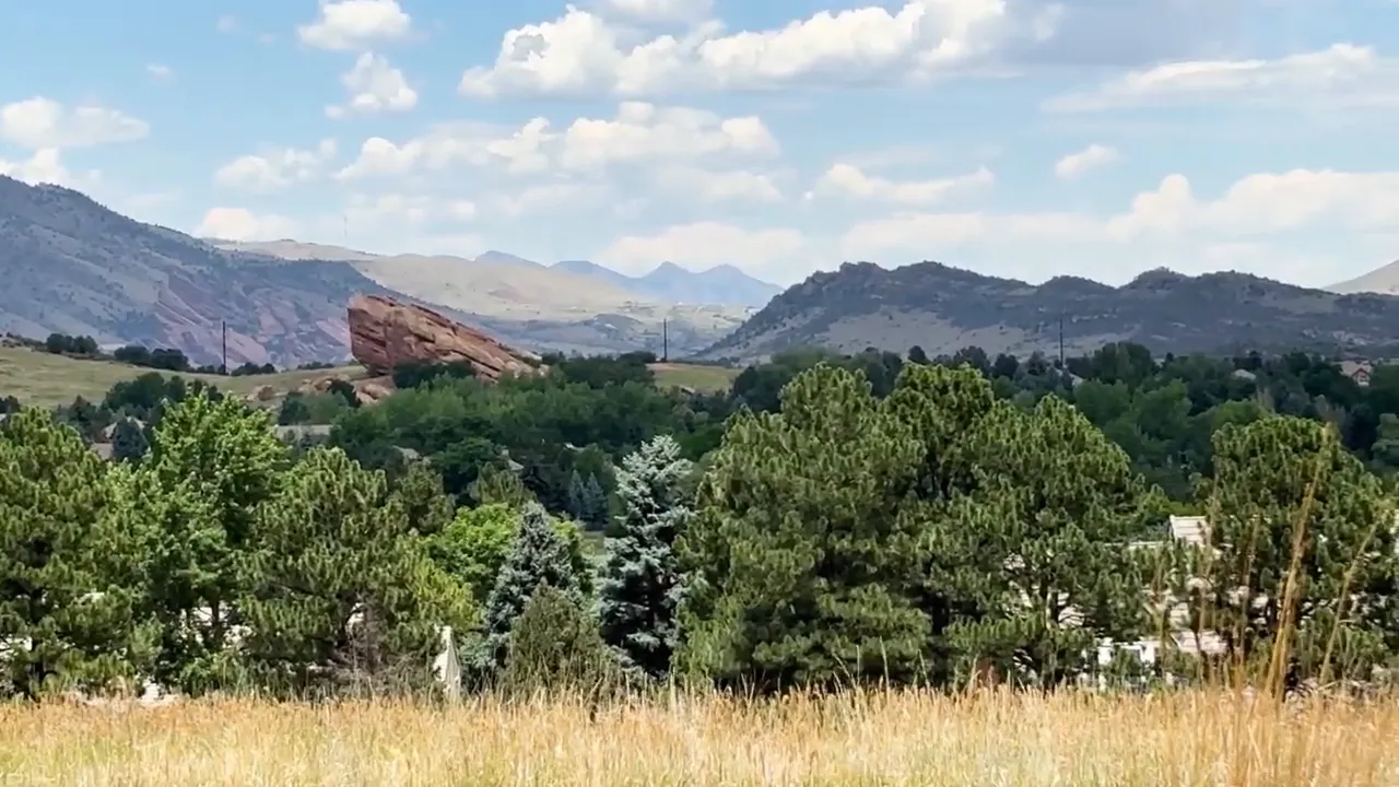 Red rock foothills rising behind trees and homes