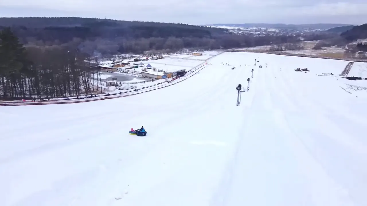 wide snow tubing hill with riders and lift lanes at a winter recreation area