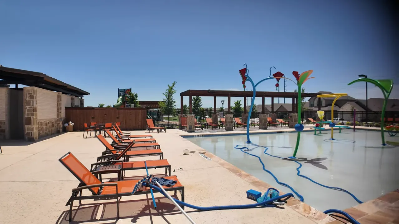 Splash pad with colorful water features beside pool deck and lounge chairs