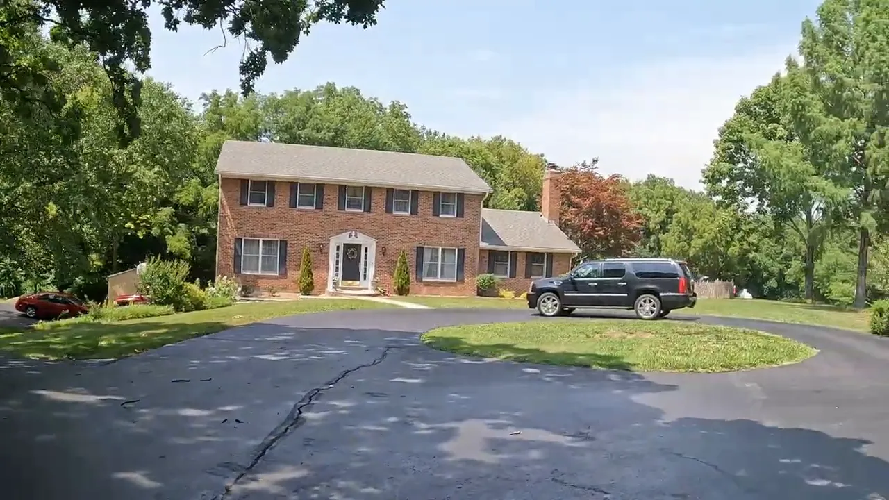 Brick two-story home with a circular driveway and large shade trees