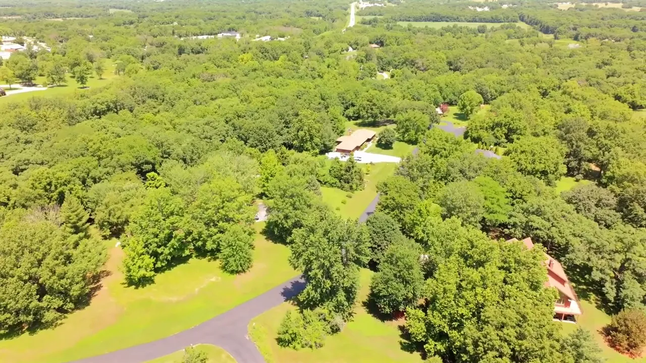 Aerial view over heavily wooded homes and winding paved roads