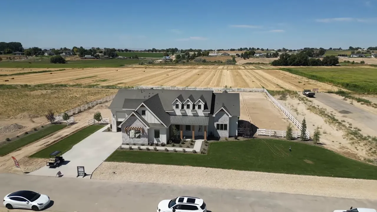 Aerial view of a large home on acreage with fenced property and open fields