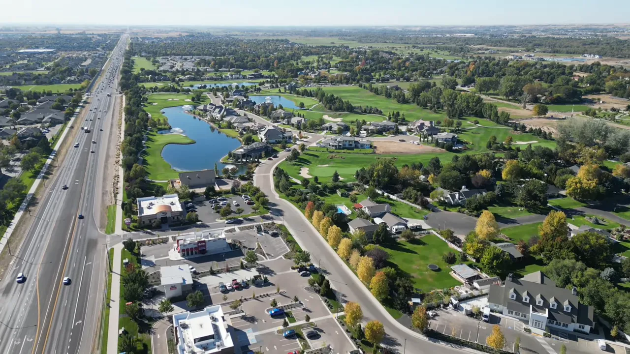 Aerial view of a planned neighborhood with a pond, golf-style landscape, and community streets near Meridian or Eagle Idaho