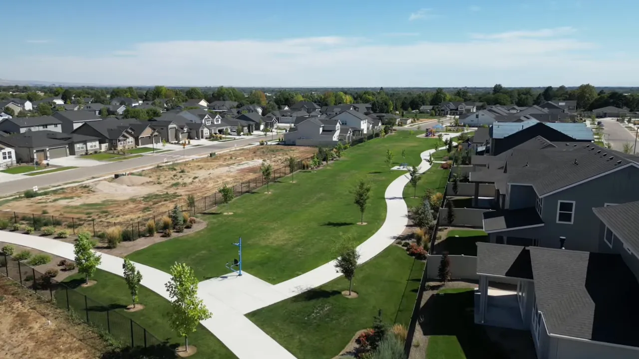 Aerial view of an upscale suburban neighborhood with a large green park and curving walking paths in Idaho