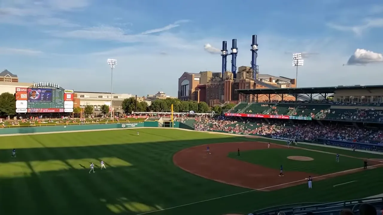 Clear wide-angle view of Victory Field during a daytime game, showing the stands, scoreboard, and stadium roof.