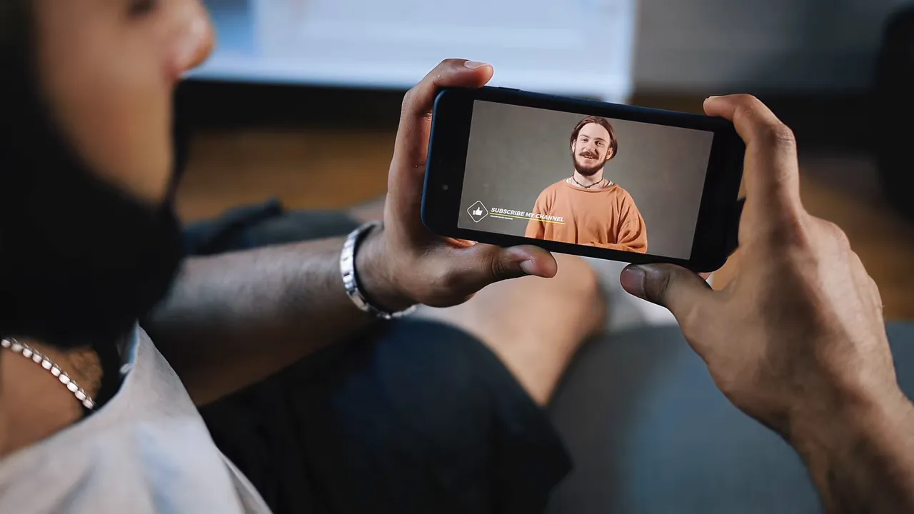 Person holding a smartphone and watching a video, illustrating mobile viewers consuming long-form and short-form content
