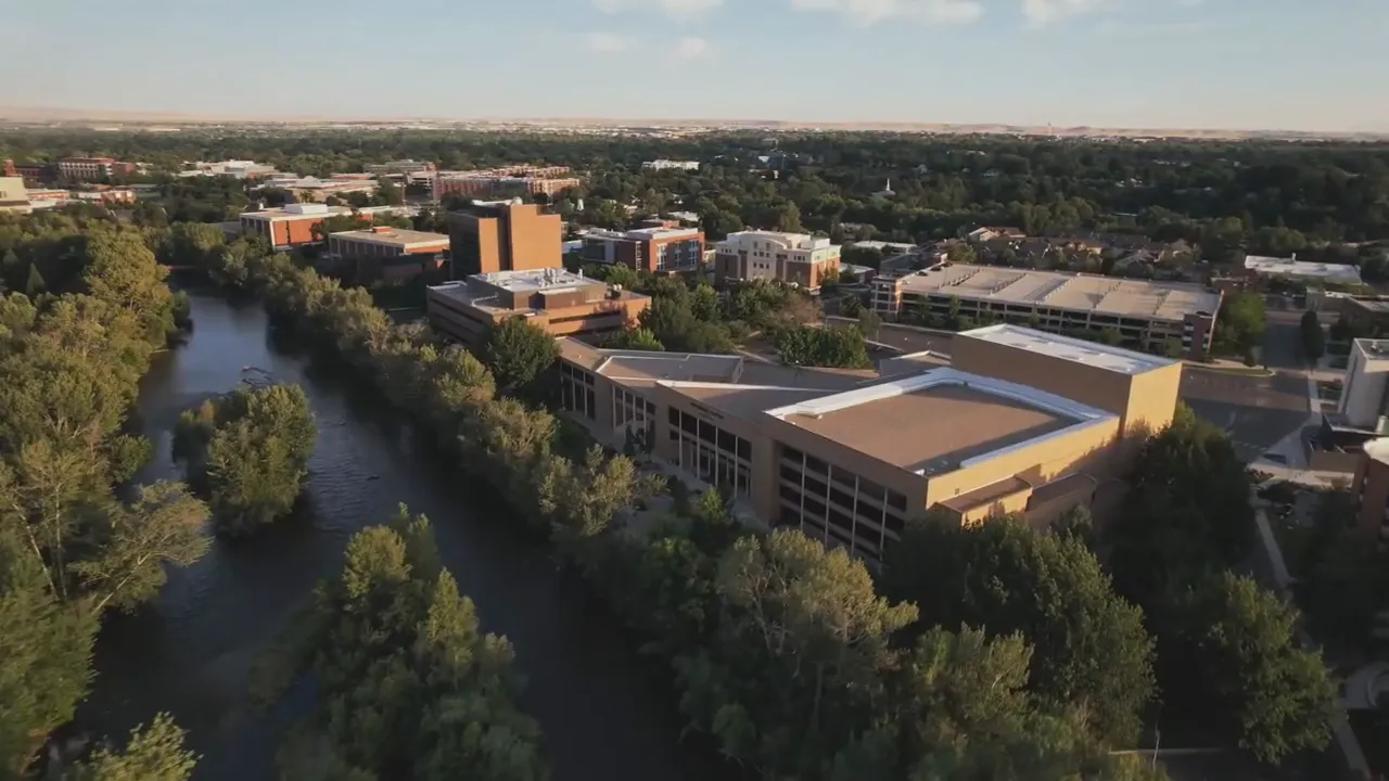 aerial view of river lined with trees beside Boise buildings
