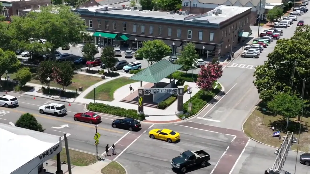 Aerial close-up of a Summerville intersection with cars, crosswalks, pedestrians and the town pavilion sign