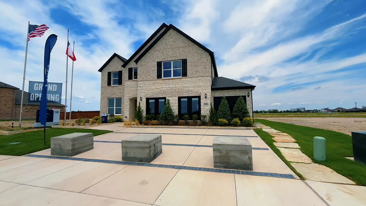 Front exterior of a two story brick home with wide driveway and open space around the lot