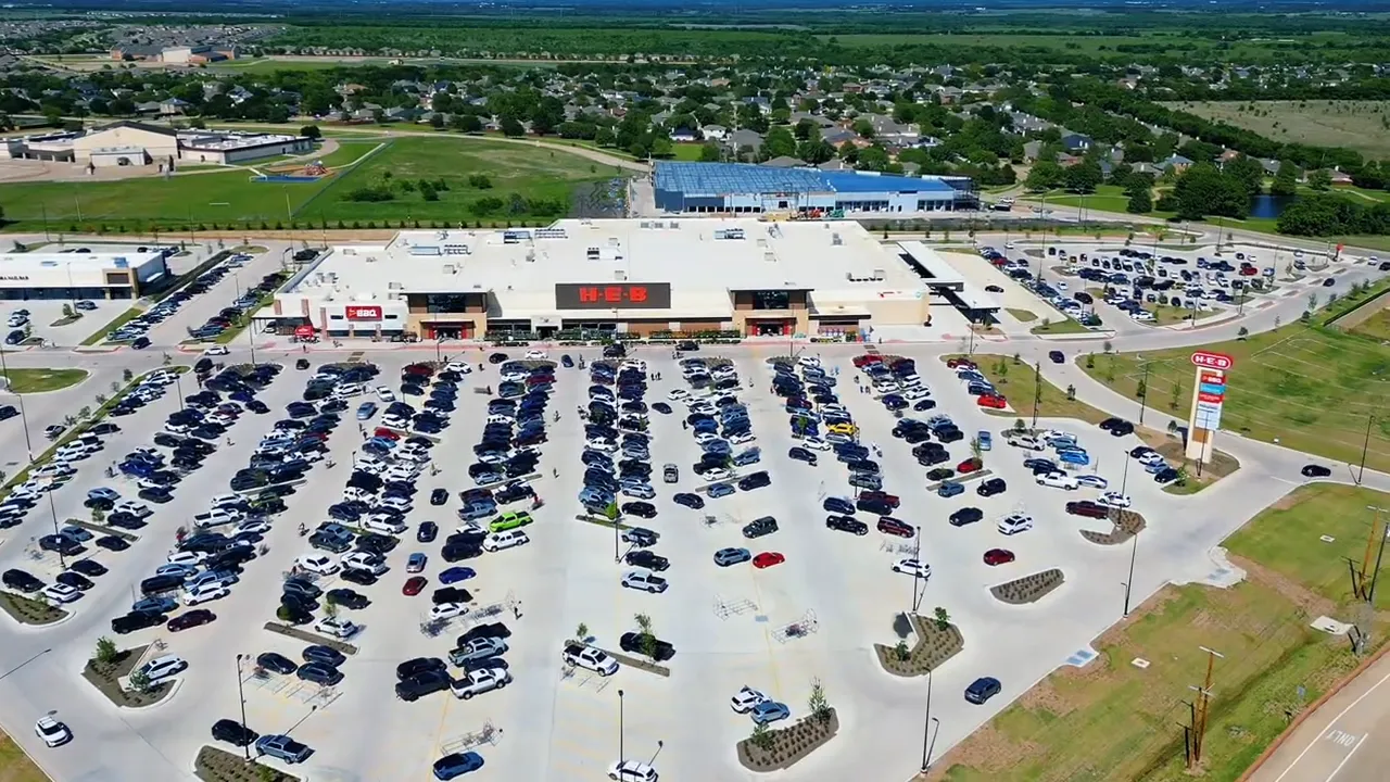 Large shopping center with full parking lot and multiple storefronts viewed from above