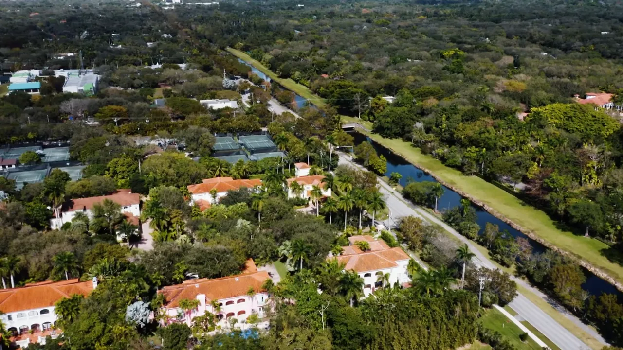 Aerial view of Pinecrest estate properties surrounded by dense greenery and a private canal