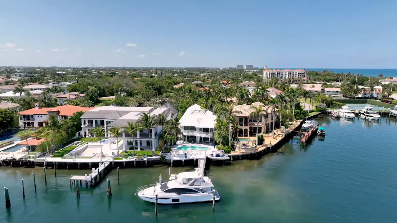 Aerial view of a luxury waterfront mansion with private dock, pools, and canal access