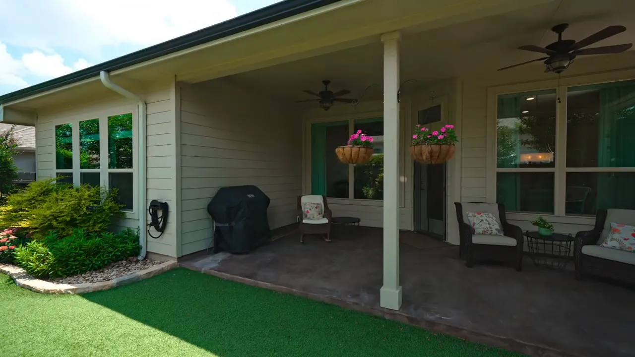 Covered patio with seating ceiling fan hanging baskets and lawn