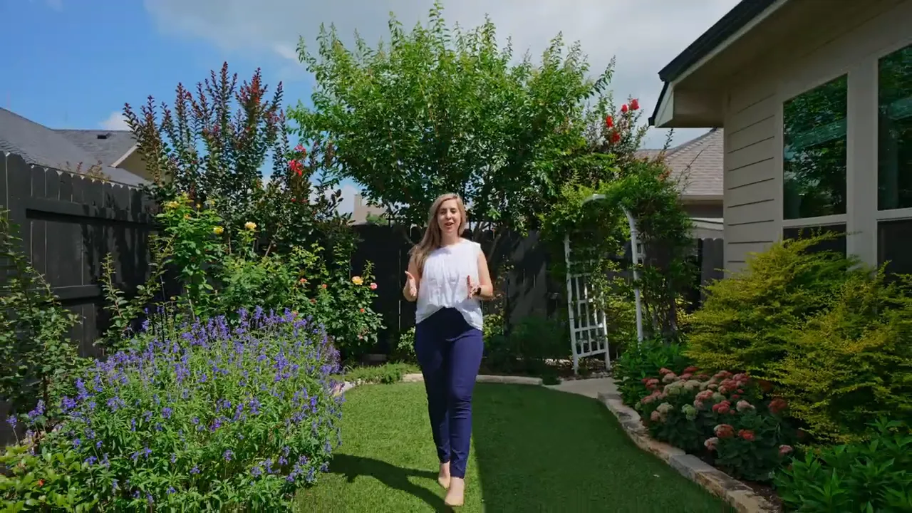 Landscaped backyard with lawn flowers shrubs and side of the home