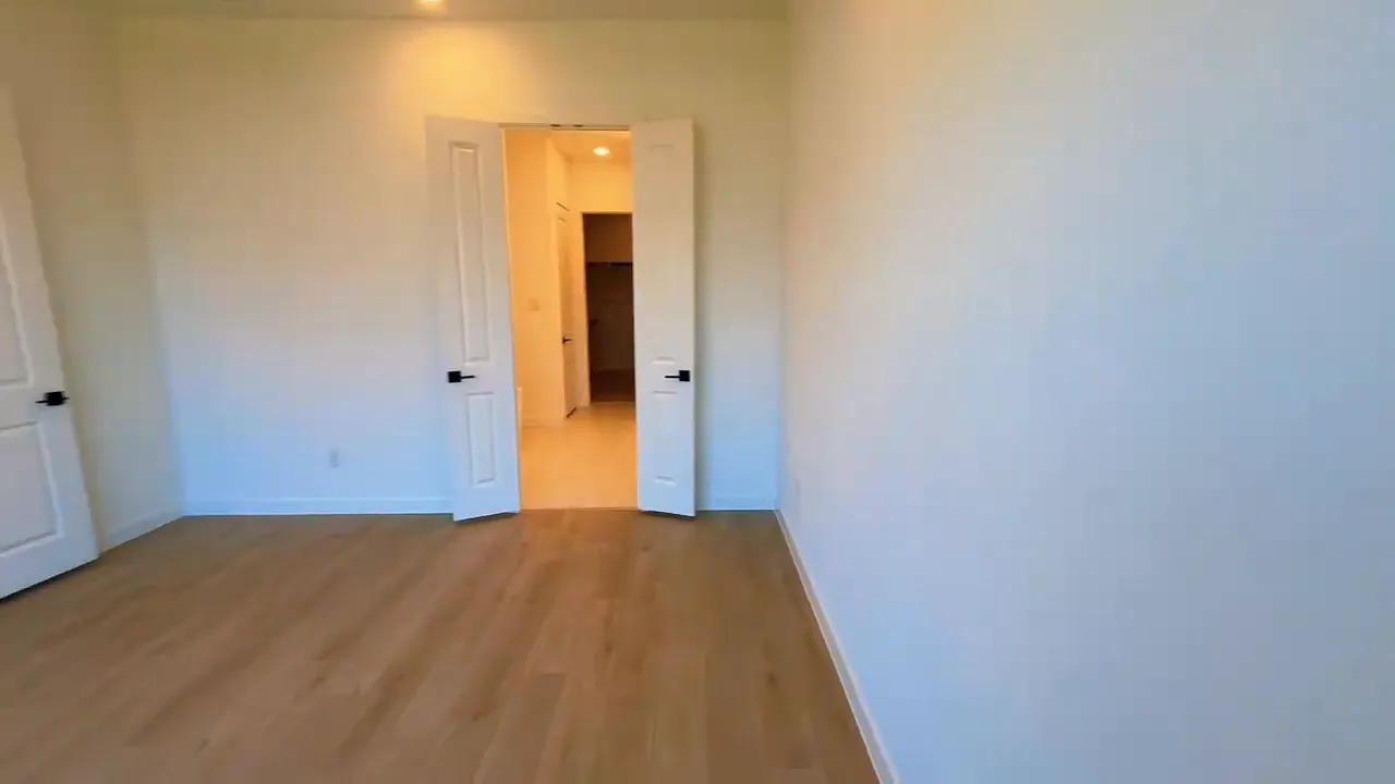 Primary bedroom with tray ceiling and double door opening to bathroom