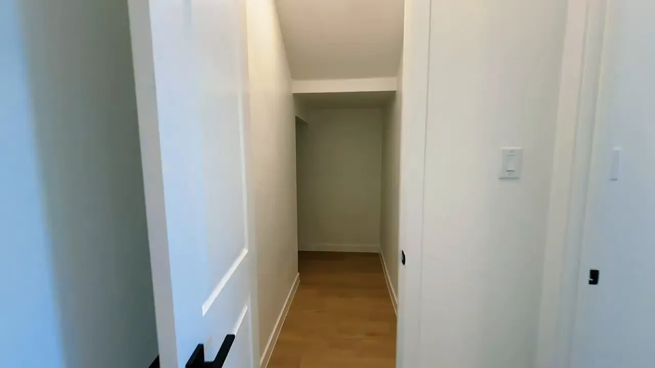 Long under stair storage hallway with white walls and wood flooring