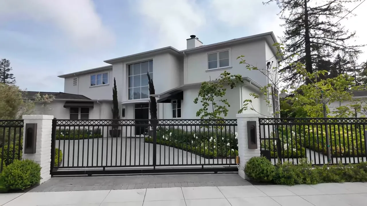 Large two story house behind a black front gate