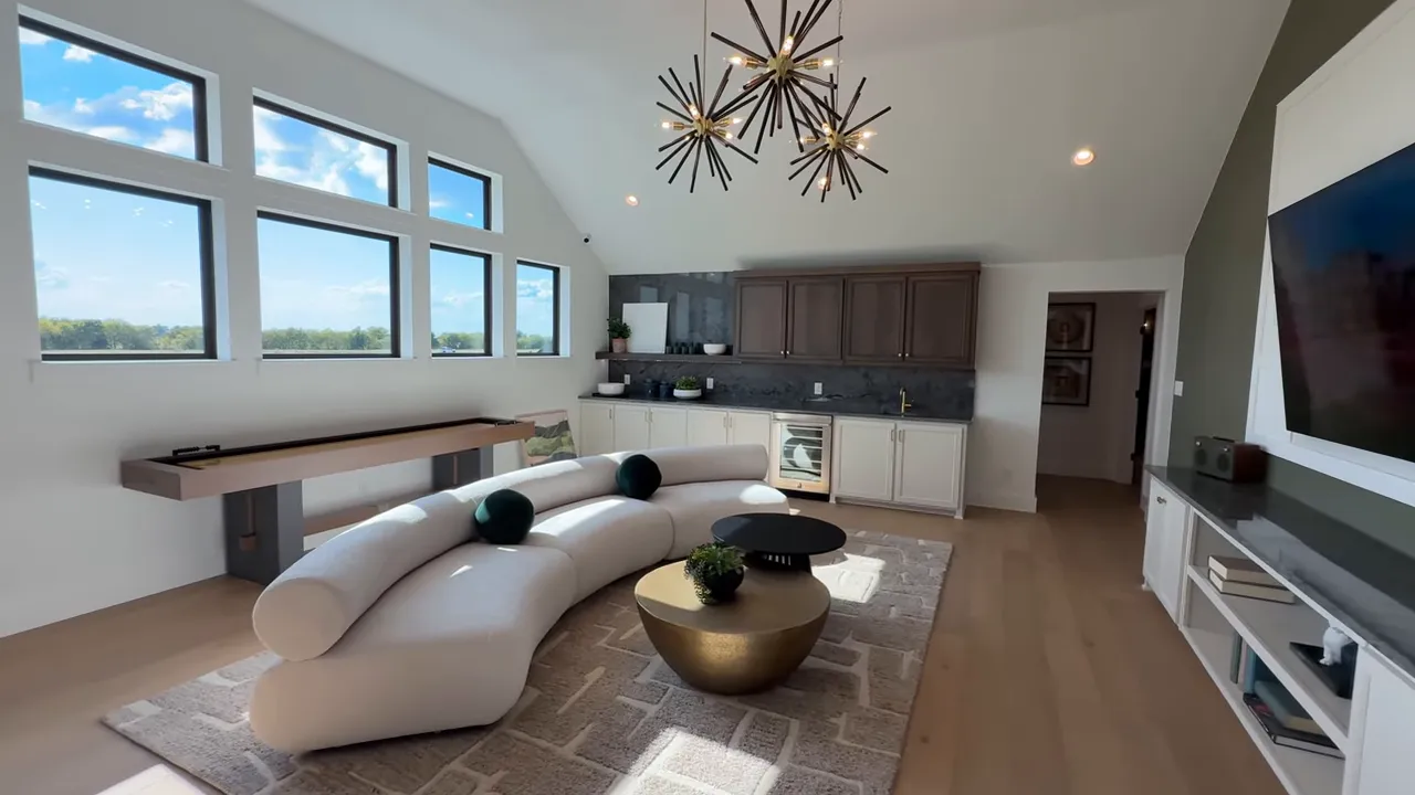 Upstairs media room with vaulted windows, curved sofa, coffee tables and wet bar
