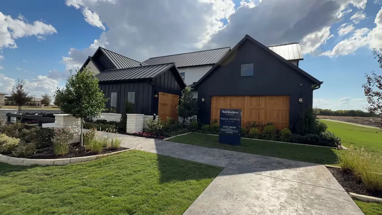 Henson farmhouse model exterior with metal roof, wood garage doors, and front landscaping at Ridgepointe Estates.