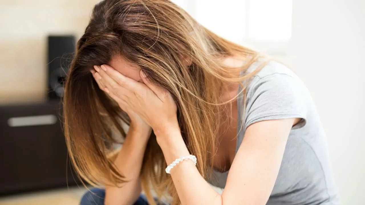 Person covering face looking distressed indoors