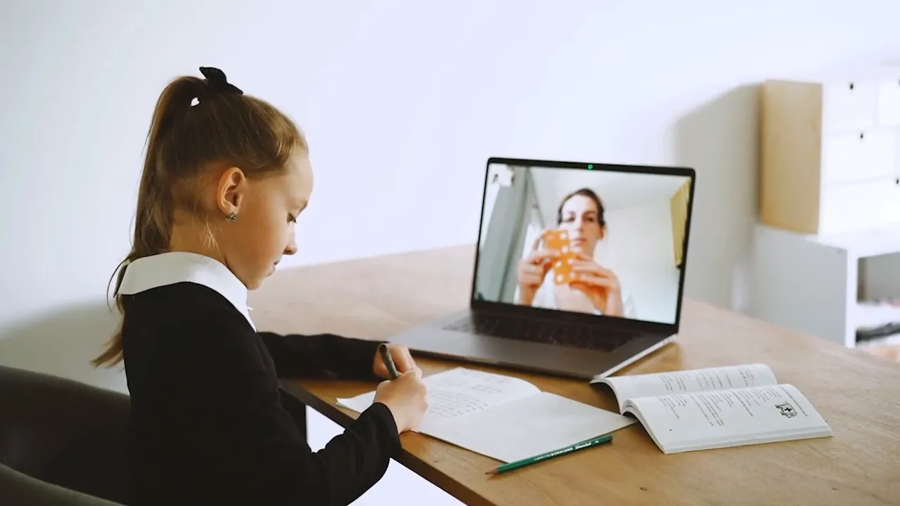 Woman taking notes during a video call on a laptop while caring for family documents