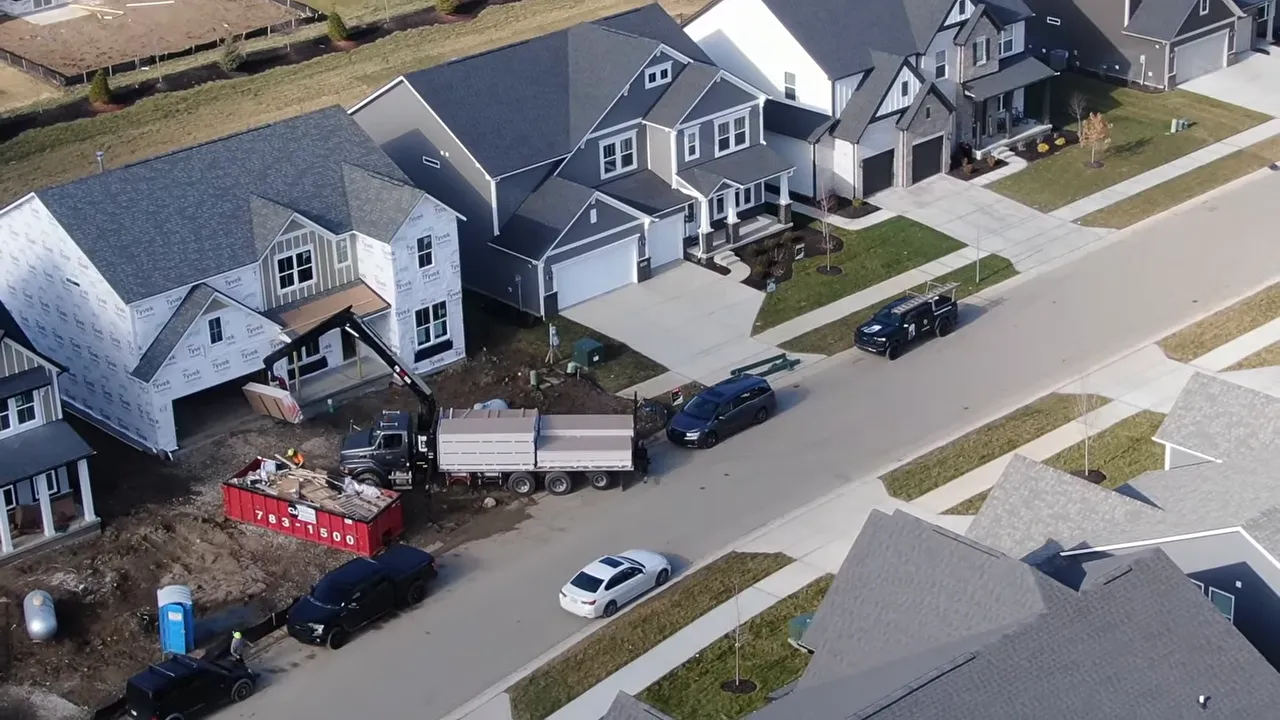 Aerial drone shot of a neighborhood of new houses under construction with trucks and driveways