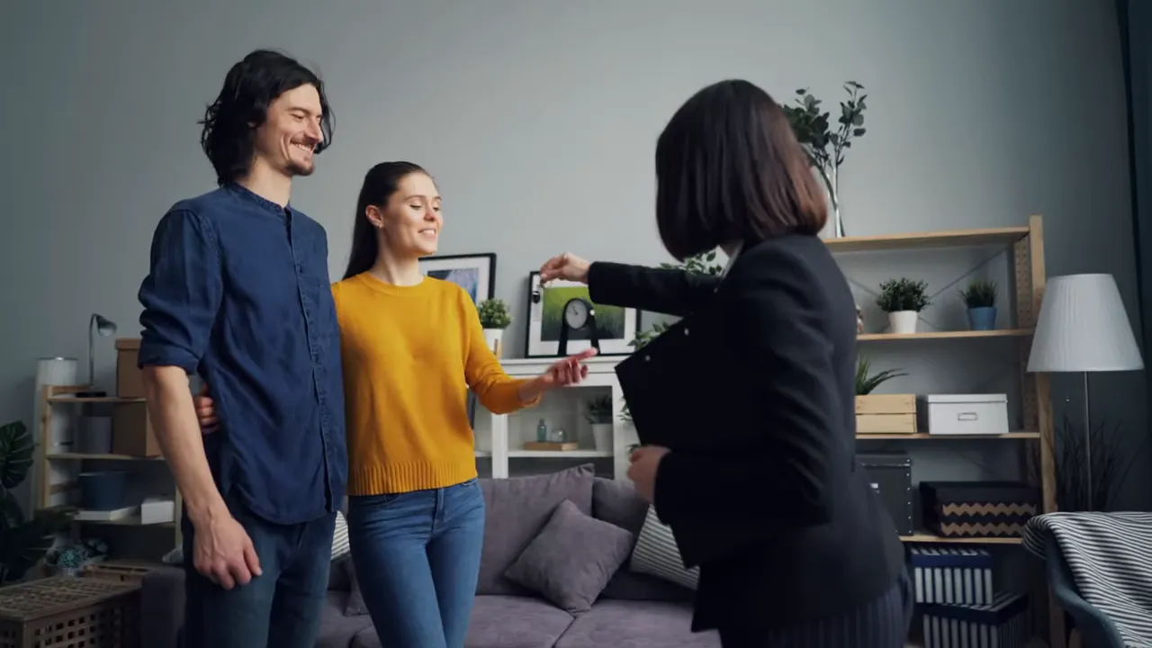 Real estate agent handing keys to a smiling couple in their new home living room