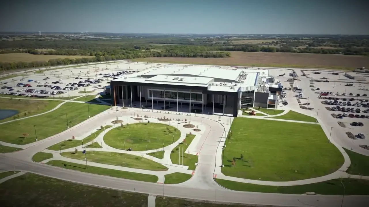 Aerial photo of a large civic or amenity building with surrounding parking, lawns, and walking paths