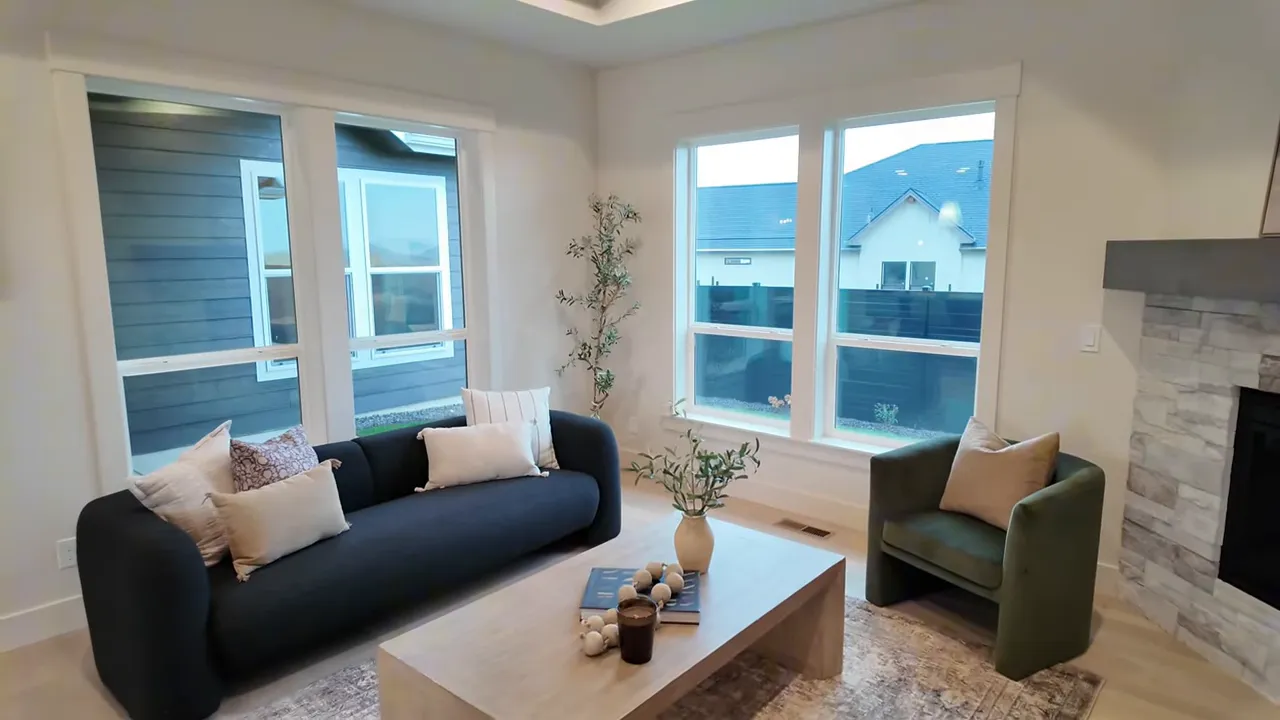 Bright living room with large windows, navy sofa, coffee table, and tray ceiling.