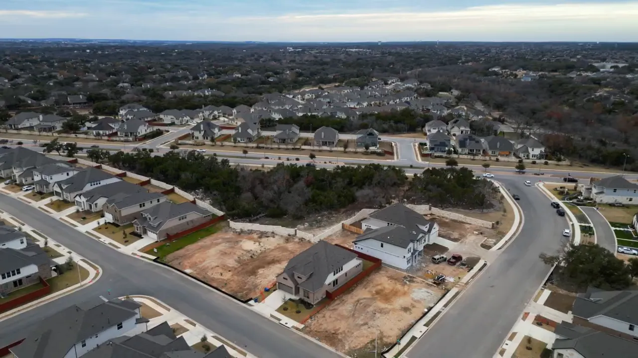 aerial view of suburban neighborhood with houses, streets, and empty lots in Cedar Park