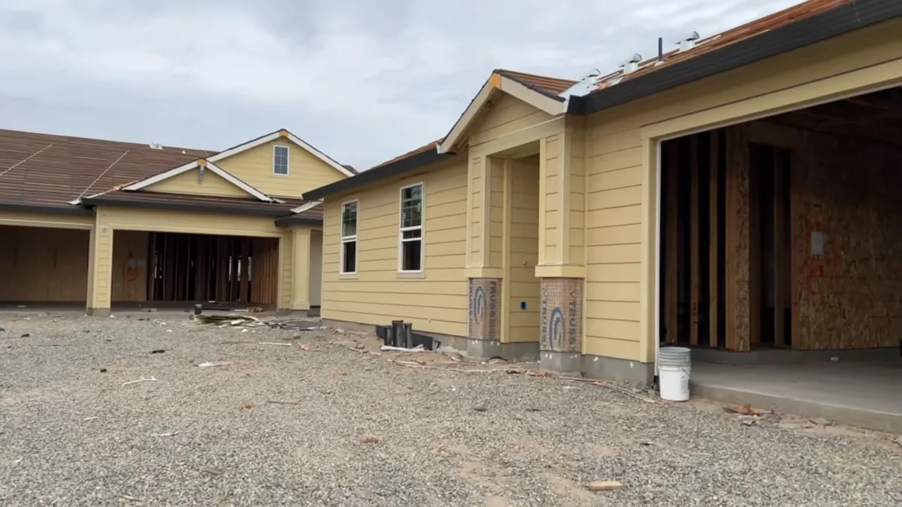 Wide shot of new-construction homes with a large gravel front yard and open garage, illustrating lot size