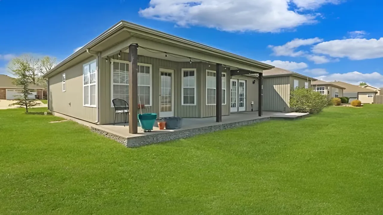 covered back patio and large grassy backyard behind ranch home