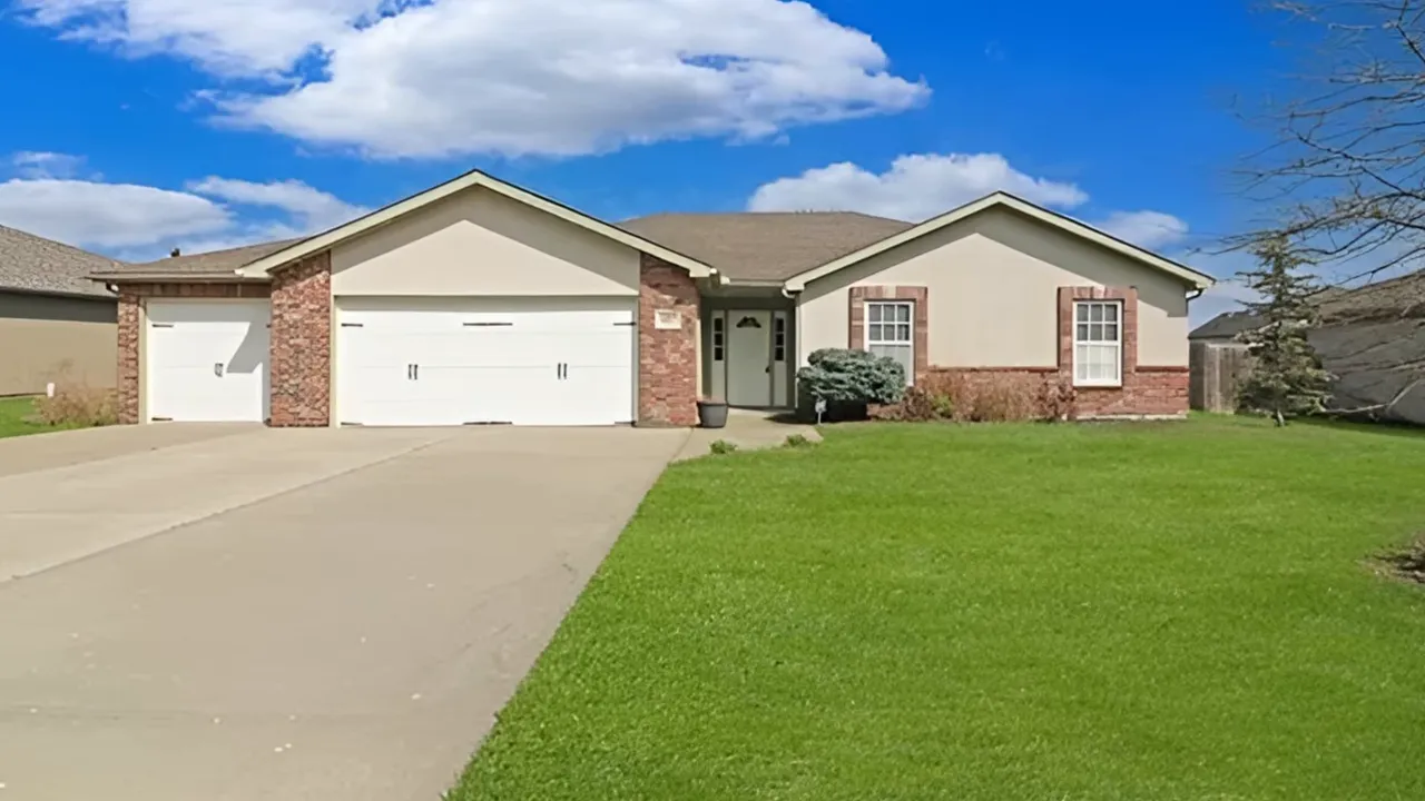 front exterior of single story ranch home with large driveway and green lawn