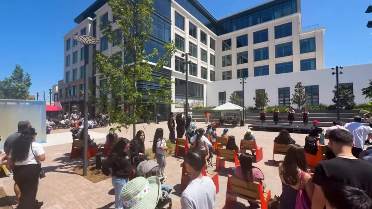 Crowd gathered in Burlingame Town Square with modern office building behind