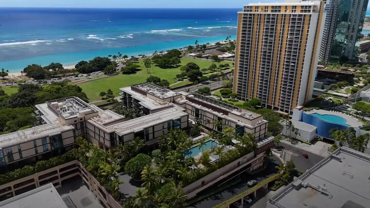Aerial view of Ward Village towers beside the ocean with price range text on screen