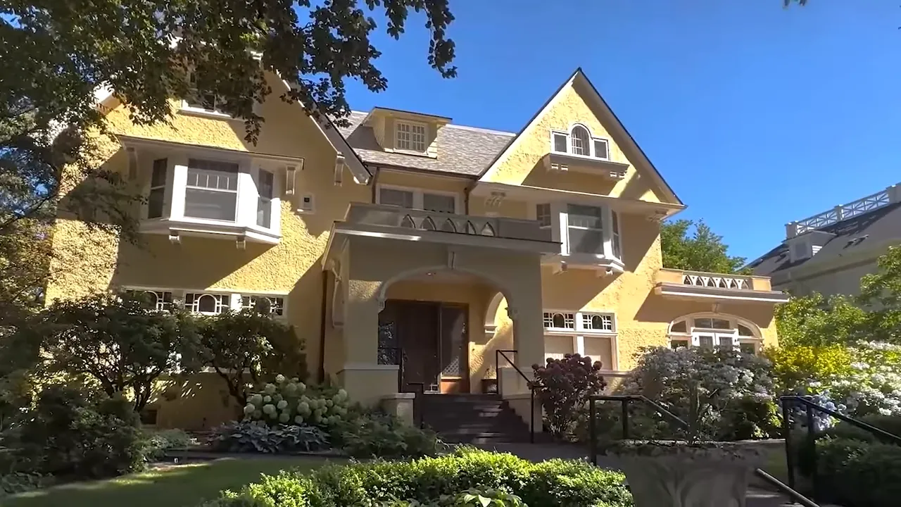 Large white historic home with tall front columns and parked cars