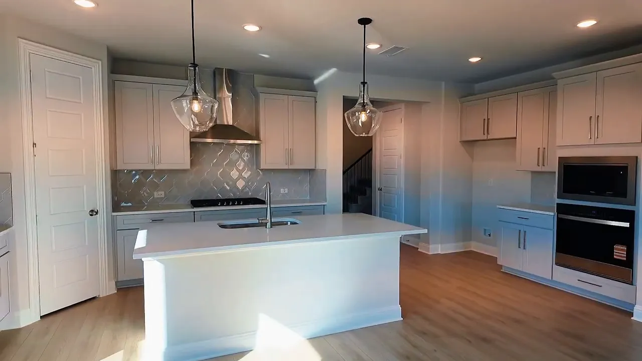 Open concept kitchen with quartz-style counters, pendant lighting, and built-in appliances in a Frisco TX new construction home