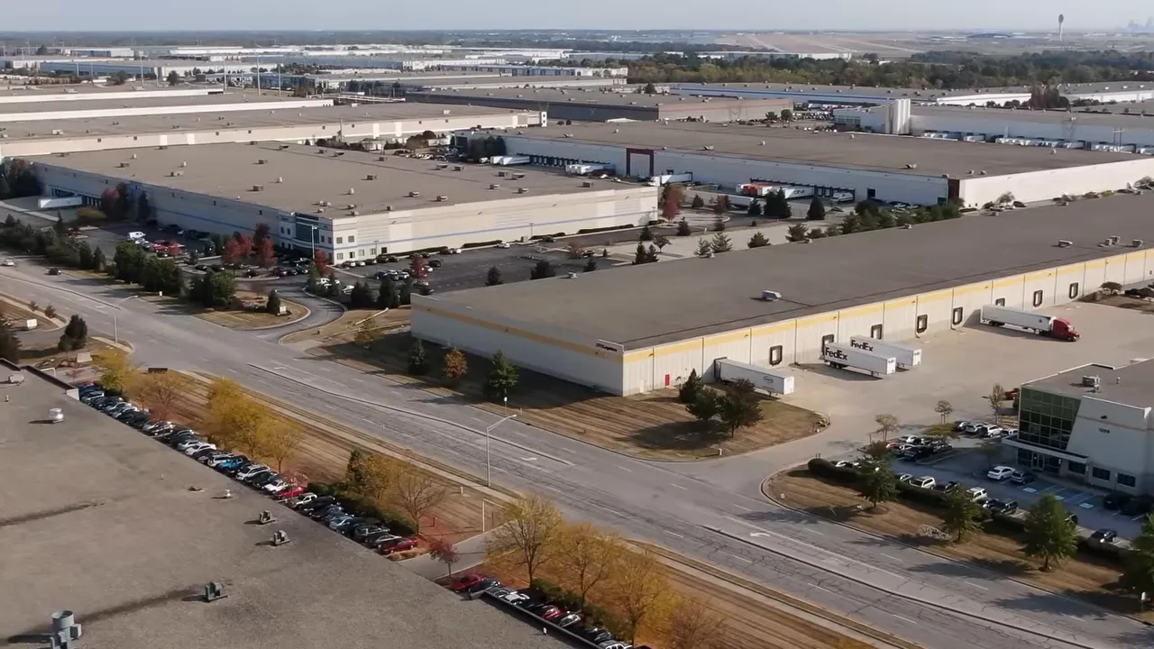 High-resolution aerial shot of large distribution centers with FedEx trailers and loading docks near the airport