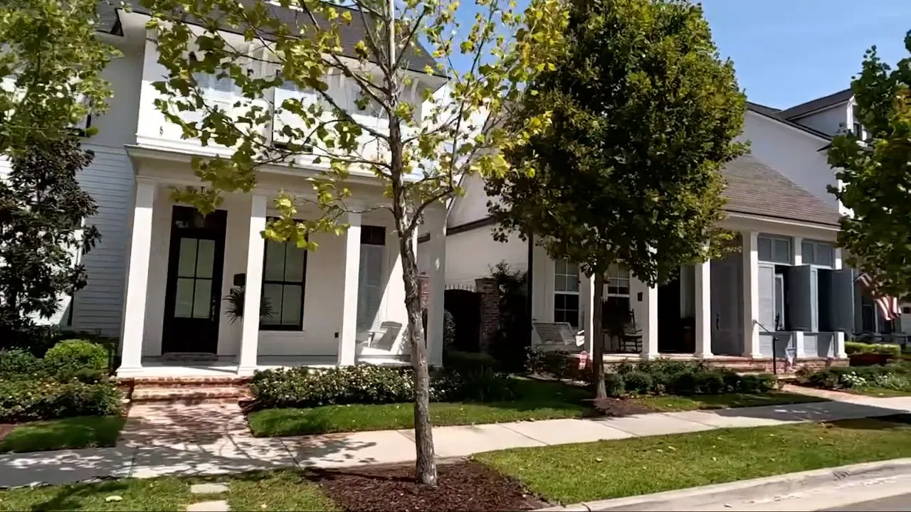 Street view of Baton Rouge-style homes with front porches, trees and sidewalks on a sunny day