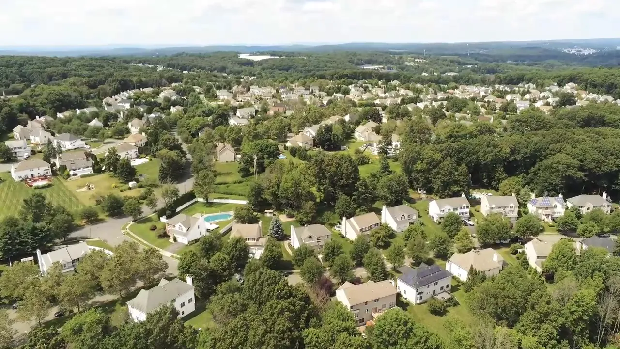 Aerial drone view of a suburban neighborhood in Morris County showing houses, yards and surrounding woods