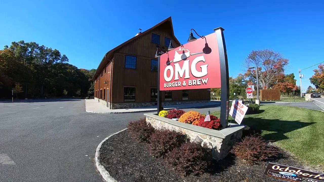 Sign for omg burger and brew in front of a brown building with flowers