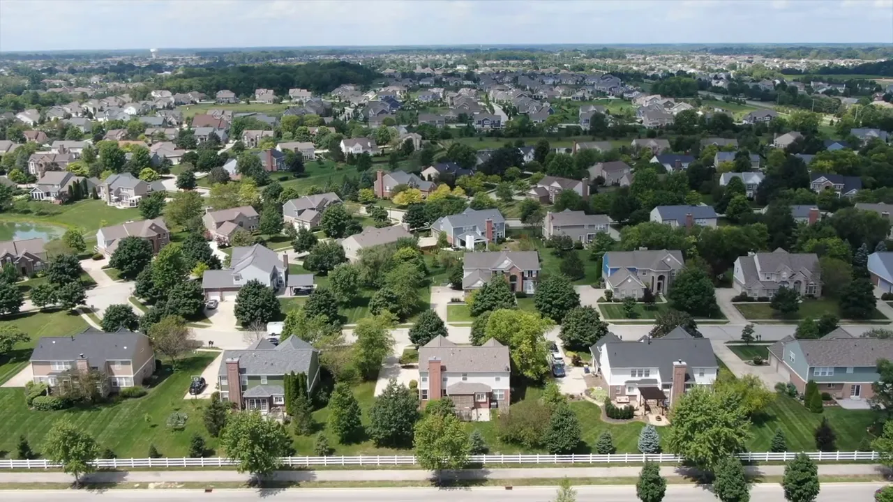Aerial view of newer homes beside a winding green drainage corridor