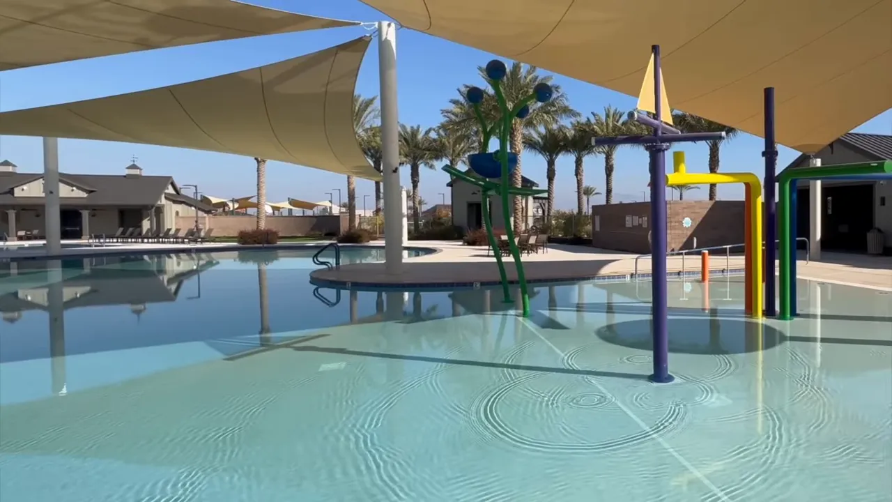 Shaded splash pad and community pool with colorful water features